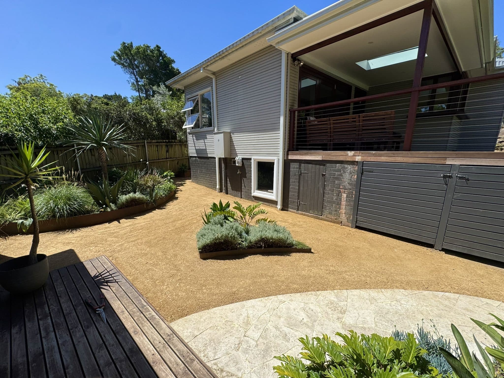 A backyard landscaped with new garden beds and a deck